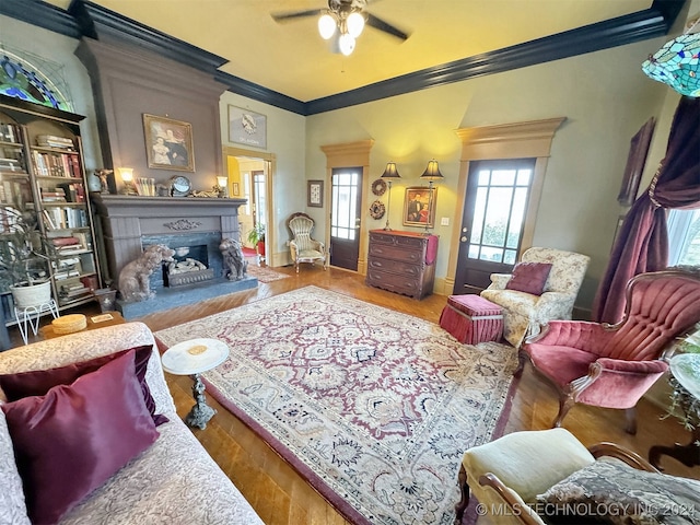 living room with ornamental molding, ceiling fan, and wood-type flooring