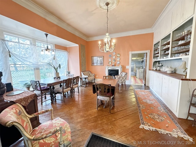 dining area with an inviting chandelier, hardwood / wood-style flooring, and ornamental molding