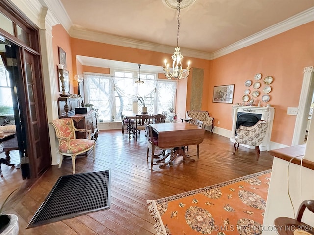 dining room with wood-type flooring, ornamental molding, and a notable chandelier