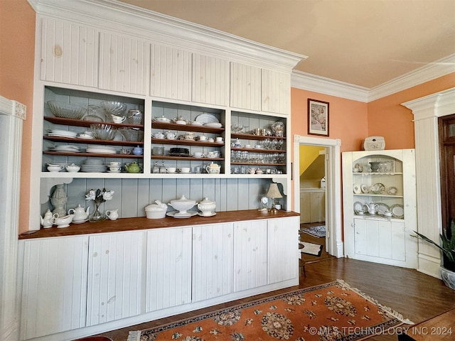 bar featuring ornamental molding and dark wood-type flooring