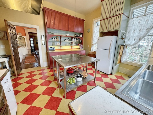 kitchen featuring stainless steel counters, white refrigerator, plenty of natural light, and dark wood-type flooring