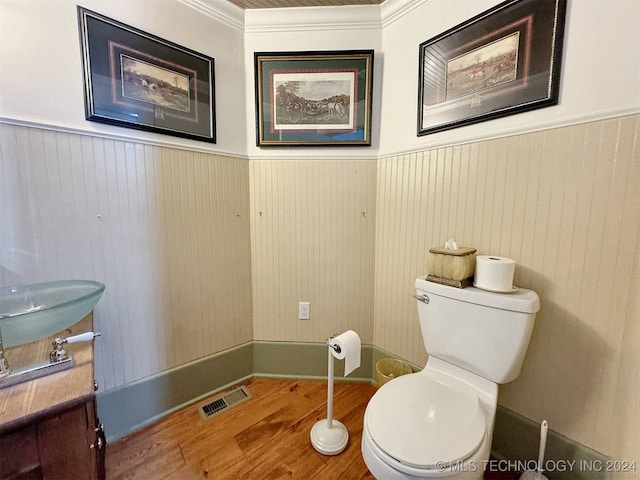 bathroom featuring wood walls, ornamental molding, hardwood / wood-style flooring, and toilet