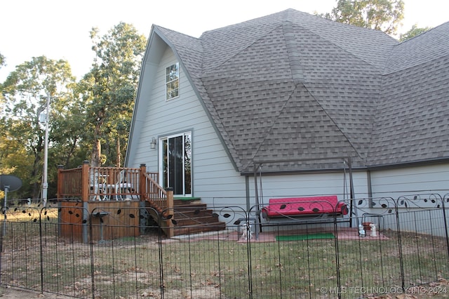 back of house with a garage, a wooden deck, and a yard