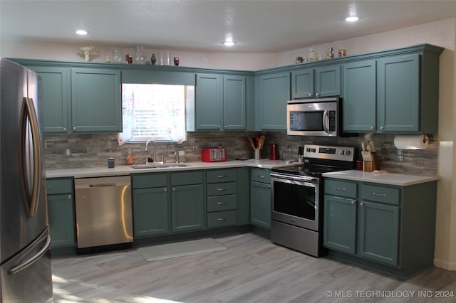 kitchen featuring appliances with stainless steel finishes, backsplash, sink, and light hardwood / wood-style flooring