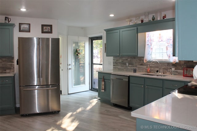 kitchen featuring appliances with stainless steel finishes, backsplash, sink, and light hardwood / wood-style flooring