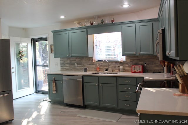 kitchen featuring stainless steel appliances, light wood-type flooring, sink, and a wealth of natural light