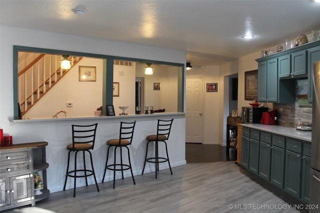 kitchen featuring hardwood / wood-style flooring, backsplash, and a kitchen bar