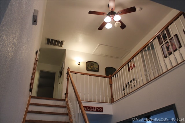 staircase with a high ceiling and ceiling fan