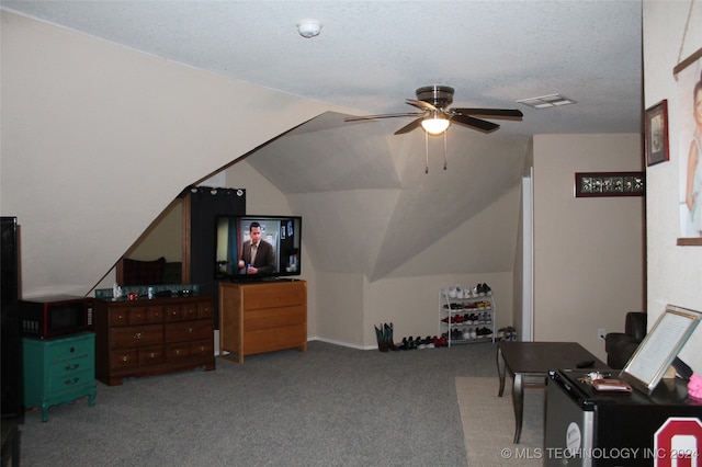 interior space with ceiling fan, vaulted ceiling, carpet, and a textured ceiling