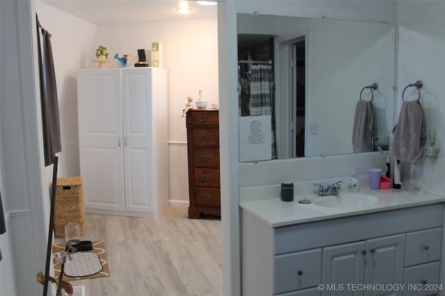 bathroom featuring wood-type flooring, vanity, and tasteful backsplash