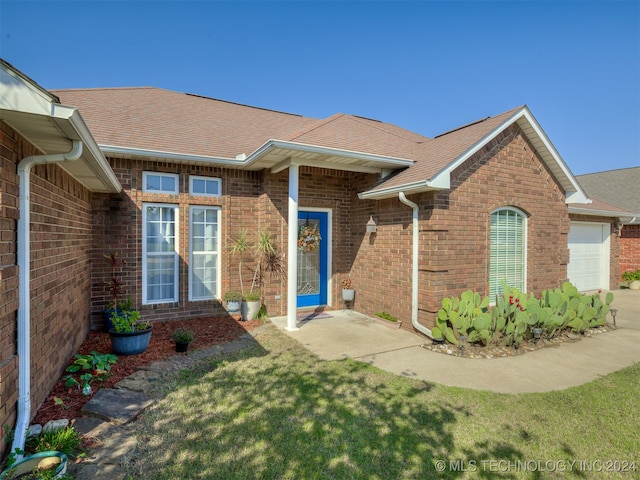 property entrance featuring a garage and a lawn