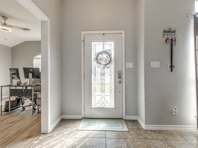 foyer entrance featuring ceiling fan, light wood-type flooring, and vaulted ceiling