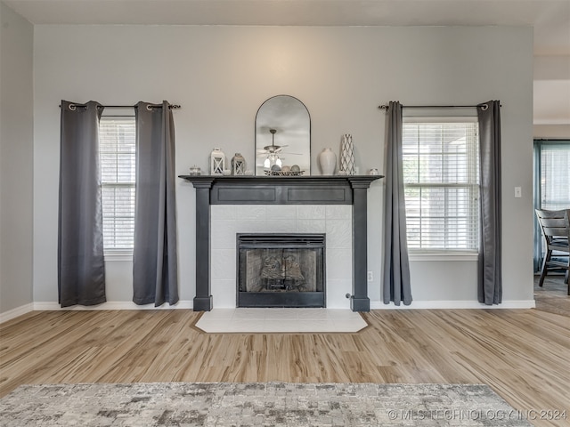 interior details featuring ceiling fan, hardwood / wood-style flooring, and a tile fireplace