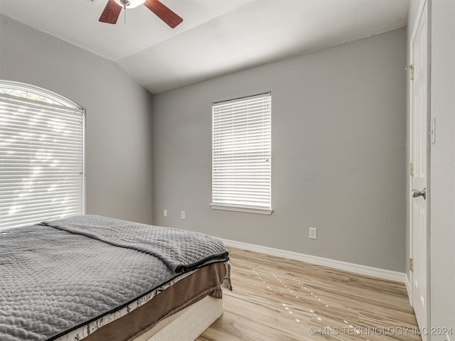 bedroom featuring ceiling fan, light wood-type flooring, multiple windows, and lofted ceiling