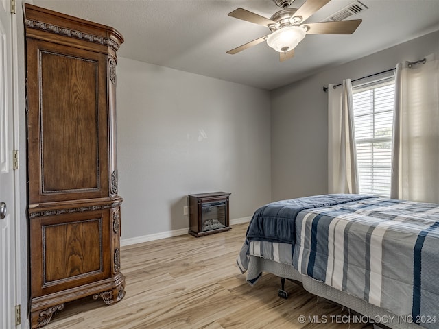 bedroom featuring light hardwood / wood-style flooring, a textured ceiling, and ceiling fan