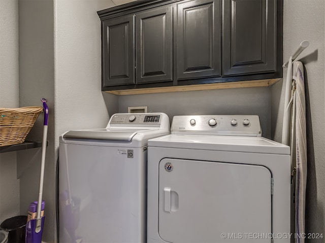 clothes washing area with washing machine and dryer and cabinets