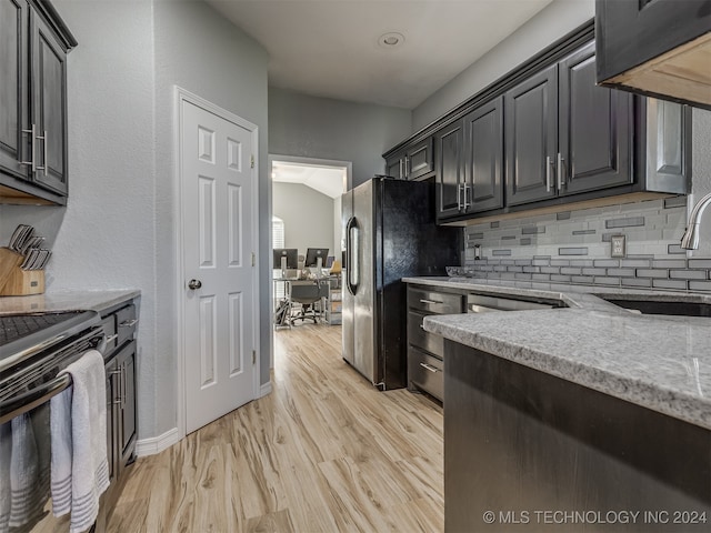 kitchen featuring light hardwood / wood-style floors, tasteful backsplash, sink, light stone counters, and appliances with stainless steel finishes