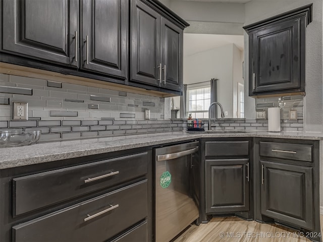 kitchen with tasteful backsplash, light hardwood / wood-style flooring, light stone counters, sink, and dishwasher