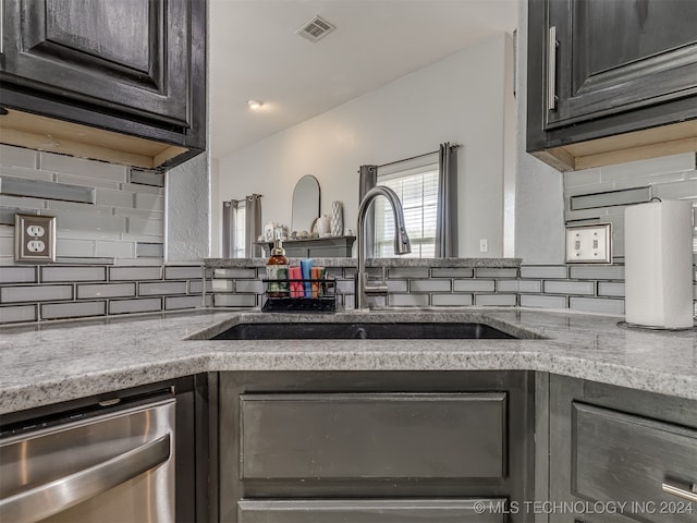 kitchen with tasteful backsplash, light stone countertops, sink, and dishwasher