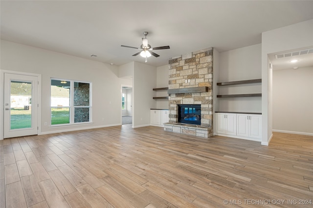 unfurnished living room with ceiling fan, a stone fireplace, and light hardwood / wood-style flooring