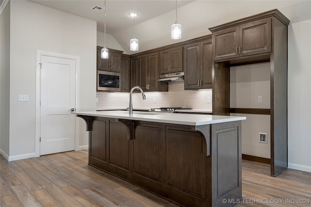 kitchen with stainless steel microwave, pendant lighting, sink, and vaulted ceiling