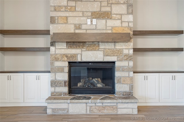 interior details with wood-type flooring and a stone fireplace