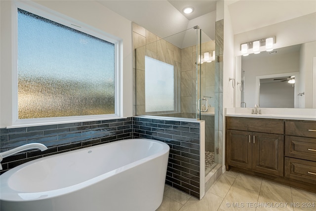 bathroom with ceiling fan, vanity, tile patterned floors, shower with separate bathtub, and tile walls