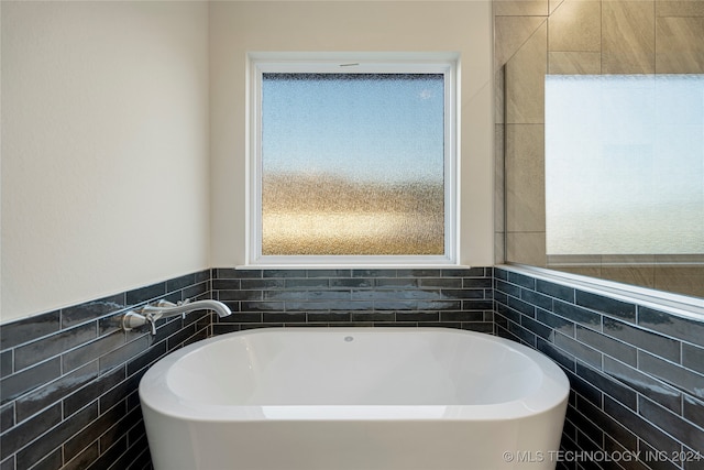 bathroom with a bathtub and tile walls