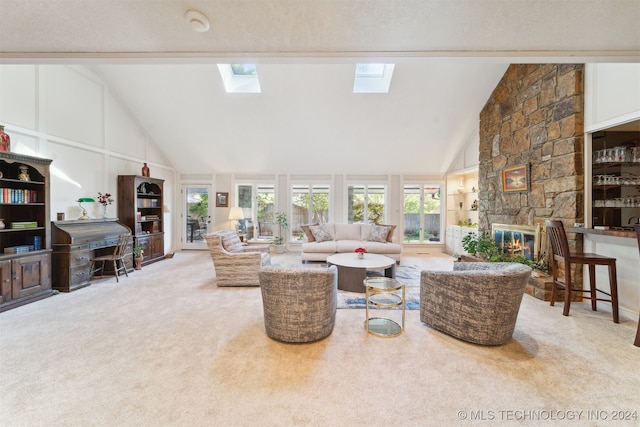 living room with carpet flooring, a skylight, a stone fireplace, a textured ceiling, and high vaulted ceiling