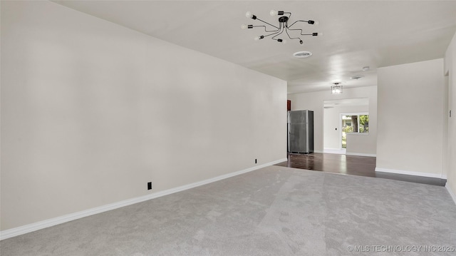 unfurnished living room with a notable chandelier and carpet floors