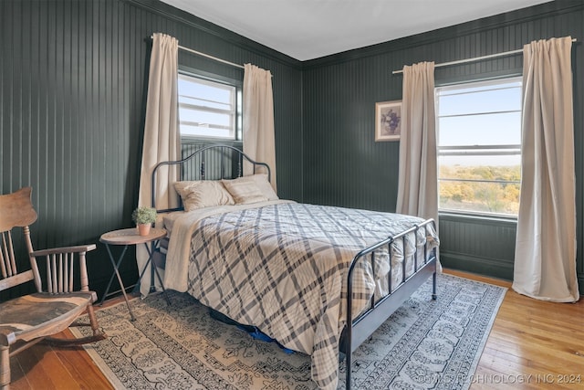 bedroom featuring hardwood / wood-style flooring, crown molding, and multiple windows