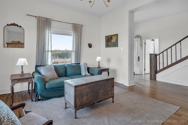 living room with wood-type flooring, a notable chandelier, and ornamental molding