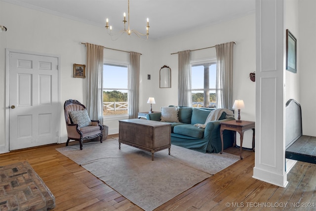 living room with a notable chandelier, ornamental molding, and light hardwood / wood-style flooring