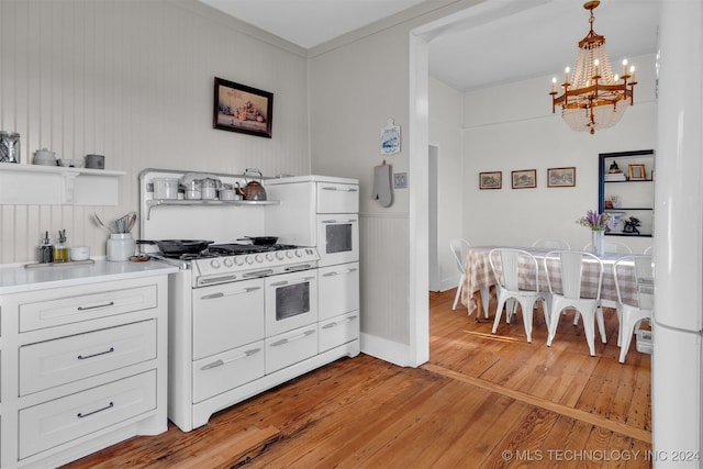 kitchen with white gas range oven, an inviting chandelier, light hardwood / wood-style flooring, decorative light fixtures, and white cabinets