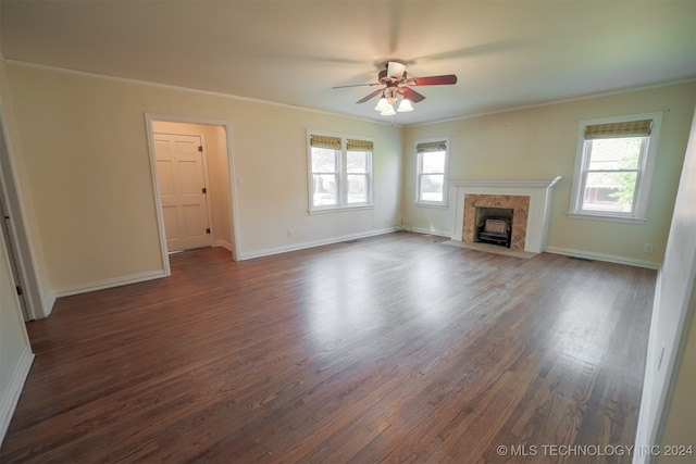 unfurnished living room featuring a healthy amount of sunlight, ceiling fan, a fireplace, and dark hardwood / wood-style floors