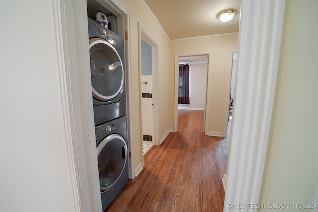 washroom featuring ornamental molding, dark hardwood / wood-style flooring, and stacked washer / drying machine