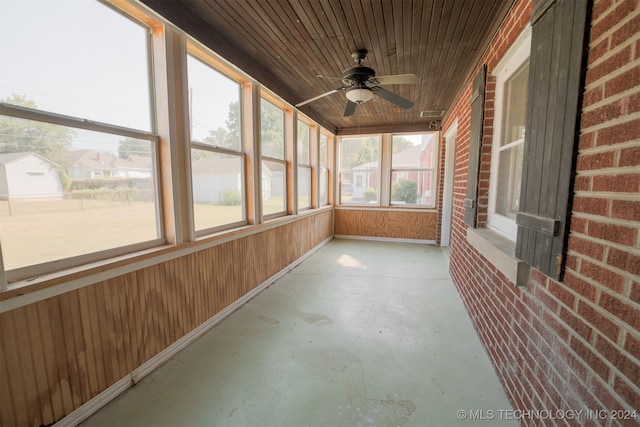 unfurnished sunroom featuring a healthy amount of sunlight, ceiling fan, and wooden ceiling