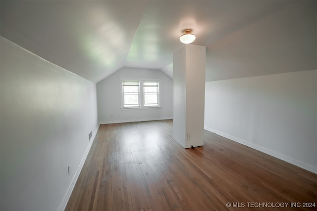 additional living space with hardwood / wood-style floors and vaulted ceiling