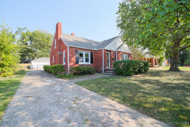 view of front of property featuring a front yard, a garage, and an outbuilding