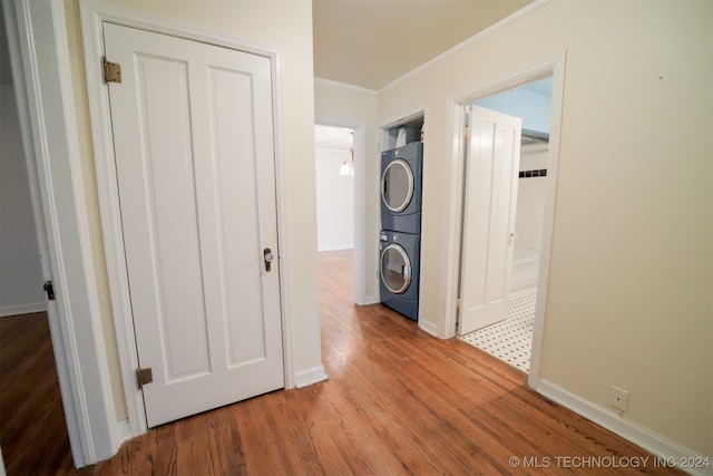 corridor featuring ornamental molding, hardwood / wood-style floors, and stacked washer / drying machine