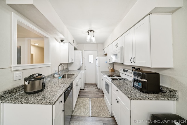 kitchen with dark stone countertops, white appliances, sink, dark hardwood / wood-style flooring, and white cabinetry