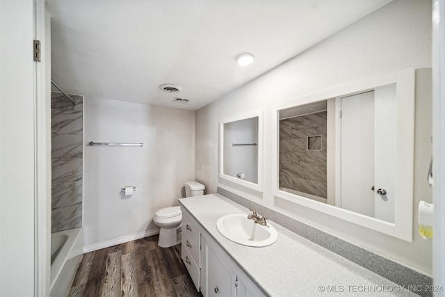 full bathroom with tiled shower / bath combo, hardwood / wood-style floors, vanity, and toilet