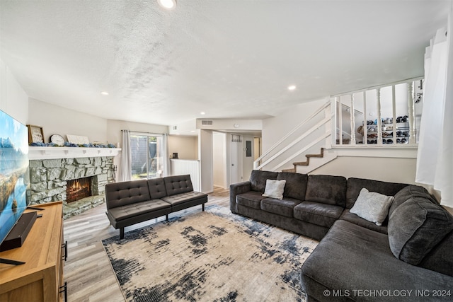 living room with a fireplace, light hardwood / wood-style floors, and a textured ceiling