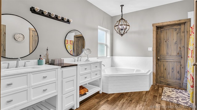 6126 Kings Rd, Ardmore, OK 73401 - bathroom featuring double vanity, a bath, wood finished floors, and a chandelier