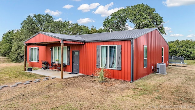 6126 Kings Rd, Ardmore, OK 73401 - rear view of house featuring a trampoline, a patio area, central air condition unit, a lawn, and metal roof