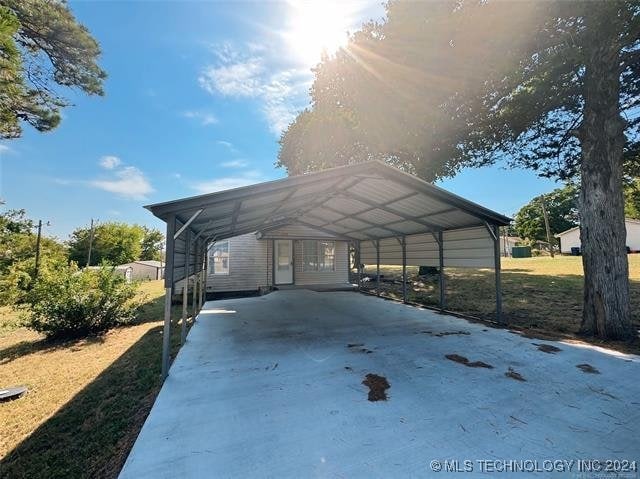 view of parking / parking lot with a yard and a carport