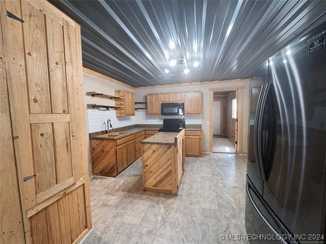 kitchen with sink, black appliances, and a center island