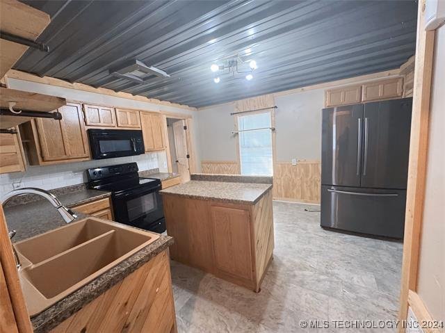 kitchen with a center island, tasteful backsplash, black appliances, and sink