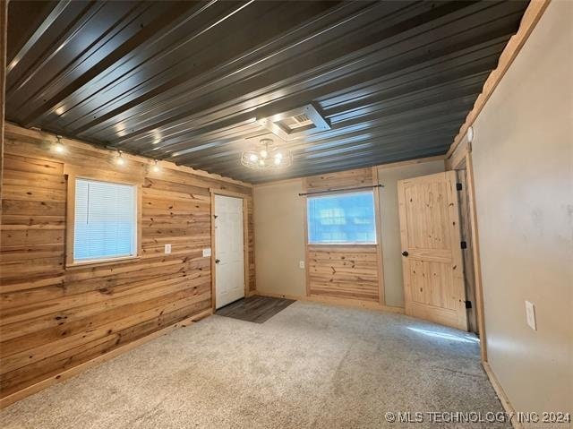 unfurnished room with carpet floors and wooden walls