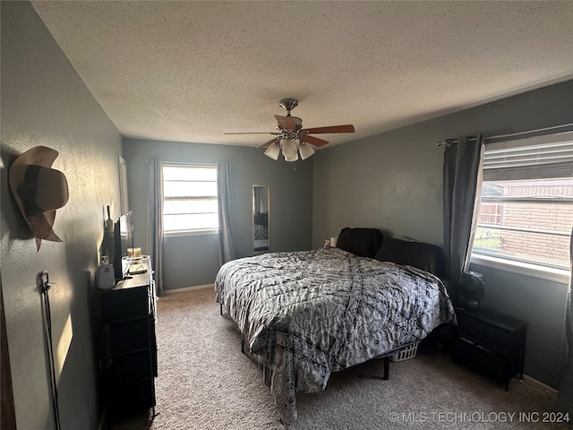 bedroom with ceiling fan, carpet floors, and a textured ceiling